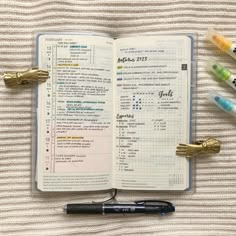 an open notebook with pens and markers on it