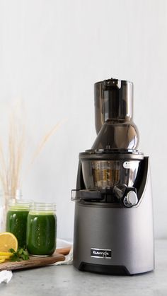 a juicer sitting on top of a counter next to some green smoothie ingredients