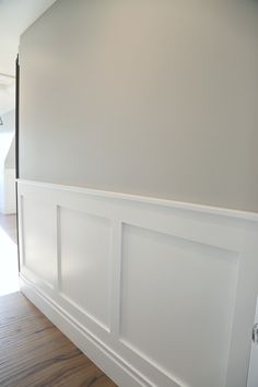 an empty room with white paneling and wood flooring on the side of the wall