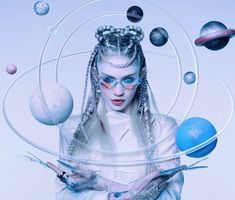 a woman with long hair holding scissors in front of planets