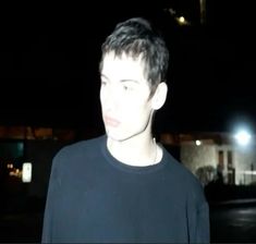 a young man standing in front of a building at night with his eyes closed and head turned to the side