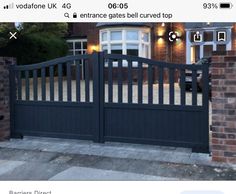 a black gate is in front of a large brick building with two windows and lights on it