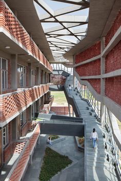 the walkway between two buildings leads to an open area with grass growing on it and people walking around