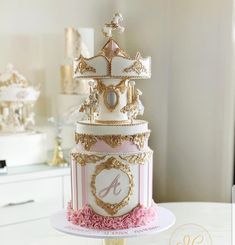 a three tiered cake with pink and gold decorations on the top, sitting on a table