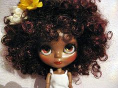 a close up of a doll with curly hair and flowers in her hair, wearing a white dress