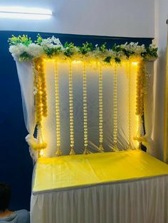 a man sitting in front of a yellow and white stage with flowers on it's head