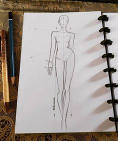 a drawing of a woman's body on top of a notebook next to a pencil