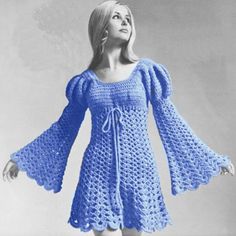 a woman in a blue crocheted dress is posing