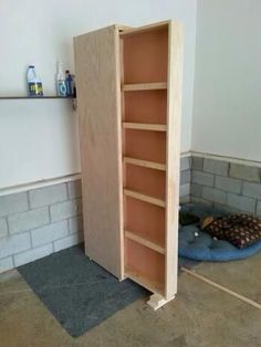 an empty bookcase in the corner of a room next to a dog bed on the floor