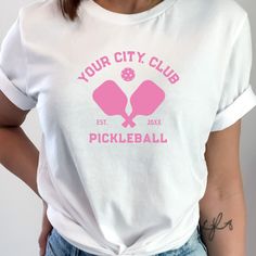 Standout on the pickleball court in this super cool t-shirt featuring crossed pickleball paddles, a ball and your custom text. Easily change the wording to include your pickleball club name, team name, city/location or any wording your choose. Also change the font and graphic colors - just click edit/personalize. Makes an awesome gift for your favorite pickleball player, team, pickleball tournament award, pickleball trip gift and everyday court wear. White T-shirt With Team Name For Pickleball, Pickleball Outfits For Women, Trendy Trucker Hats, Pickleball Aesthetic, Pickleball Tournament, Pickleball Outfit, Club Name, Pickleball Gifts, Pickleball Court