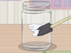 a glass jar filled with white paint and a wooden brush on top of the jar