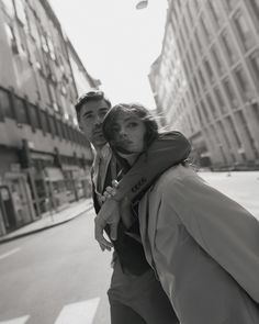 a man carrying a woman on his back down the street in front of tall buildings