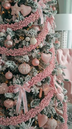 a pink christmas tree decorated with ornaments and bows