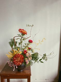 a wooden table topped with a vase filled with different types of flowers on top of it