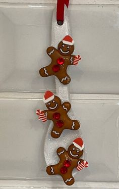 two gingerbread cookies hanging from a red ribbon on a white doorknob with candy canes