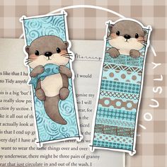 two bookmarks with otters on them, one is blue and the other is brown