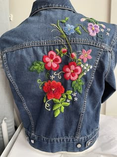 a denim jacket with embroidered flowers on it