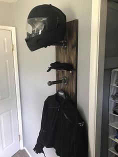 a motorcycle helmet and jacket hanging on a wooden rack in a room with white walls