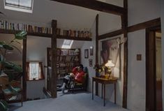 two people sitting on a couch in a room with bookshelves and a table