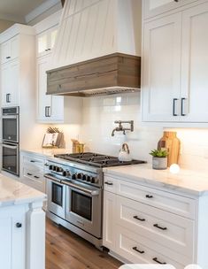 a kitchen with white cabinets and stainless steel stove top oven in the center, surrounded by wood flooring