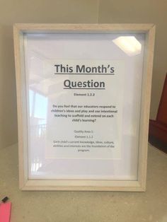 a framed sign that reads, this month's question on the wall next to a pink pen