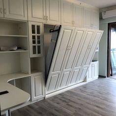 a room that has some white cabinets and shelves in it, with doors open to reveal the kitchen