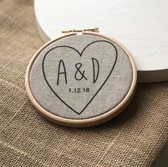 a couple's initials are on the back of a heart - shaped embroidery hoop