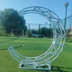 a white sculpture sitting on top of a lush green field next to a soccer field