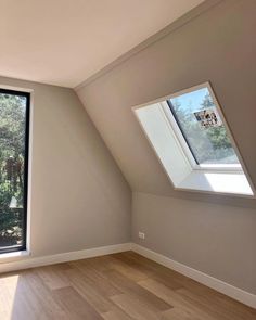 an empty room with large windows and wood flooring in front of the window is a skylight