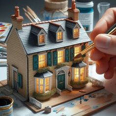 a person is holding a pen in front of a model house