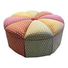 a multicolored round ottoman that is sitting on top of a white surface with polka dots