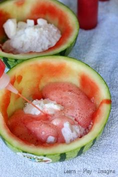 two melon halves filled with ice cream and watermelon slices on a table