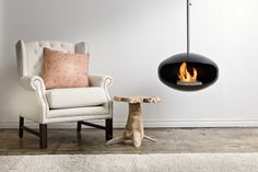 a fire pit sitting in the middle of a living room next to a white chair