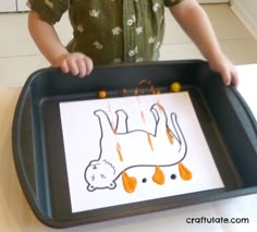 a young child holding a tray with an animal drawn on it