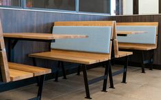 three wooden benches sitting next to each other in front of a wall with glass windows