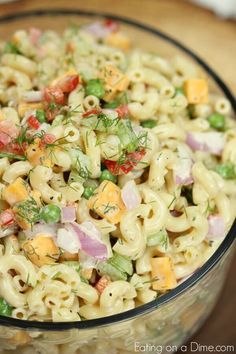 a bowl filled with macaroni salad on top of a wooden table