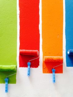 three different colors of paint being painted on the wall with rollers attached to them