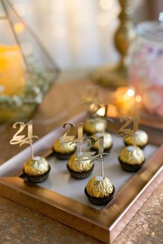 some cupcakes are sitting on a tray with candles in the backgroud