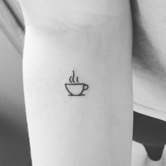 a black and white photo of a coffee cup tattoo on the left inner arm,