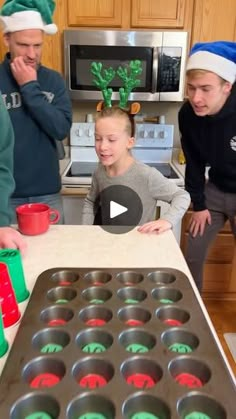 three people standing around a table with cupcakes on it