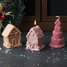 three small candles sitting on top of a table next to a christmas tree and decorations