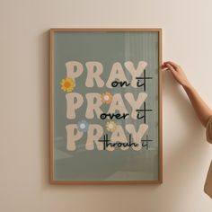 a woman holding up a framed poster with the words pray on it