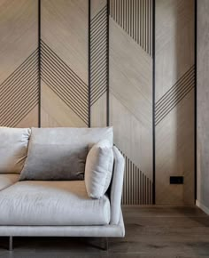 a white couch sitting in front of a wooden wall with geometric designs on it's sides