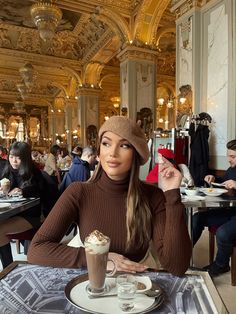 a woman sitting at a table with a cup of coffee