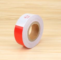 a roll of red and white tape sitting on top of a wooden table