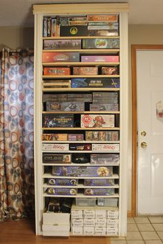 a book shelf filled with lots of books and video game's next to a door