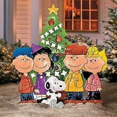 the peanuts gang standing in front of a christmas tree