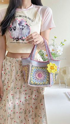 a woman is holding a purse in her hand and wearing a t - shirt with flowers on it