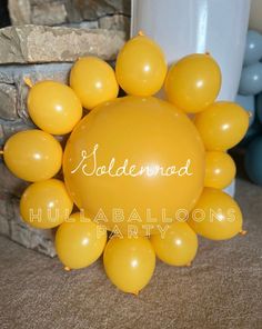 balloons are arranged in the shape of a sun on top of a brick wall, with an inscription underneath it