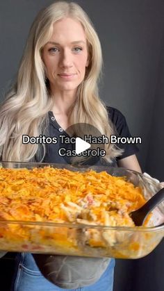 a woman holding a large casserole dish in her hands and the words doritos taco hash brown on it